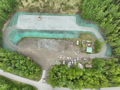 Aerial view of a parking lot with tall woodland surrounding it.