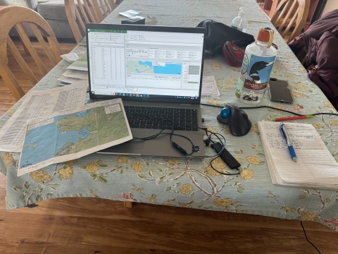 computer, maps, notebook and other materials on a table