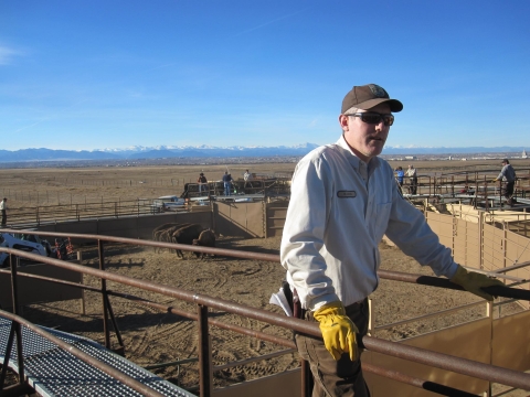 A man in a USFWS uniform, cap, and gloves walks on a ramp.