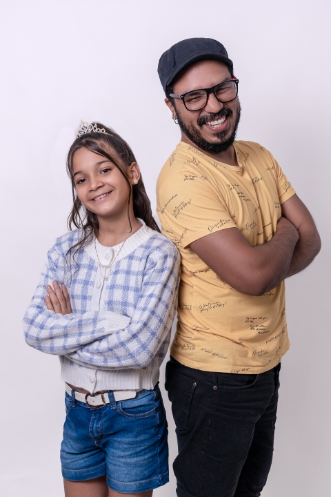 2 people stand back to back with arms crossed smiling