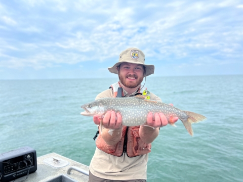 Image of person in USFWS uniform holding a lake trout.