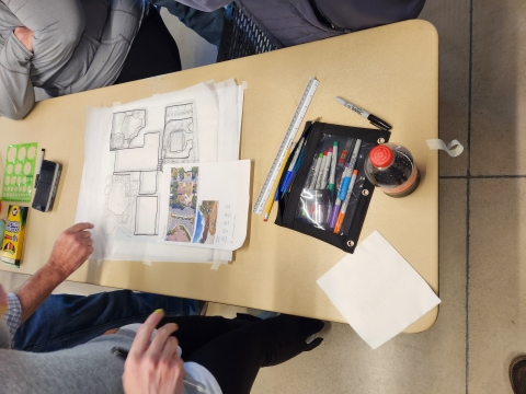 image of 3 people around a desk looking at a blueprint 