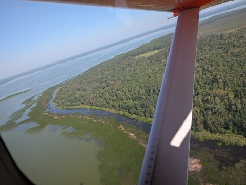 aerial view of a lake and shoreline through an airplane wing