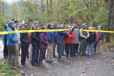 a group of people cutting a yellow ribbon.