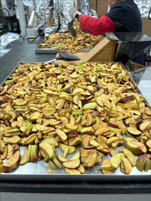 Two large trays of sliced apples and a worker pictured