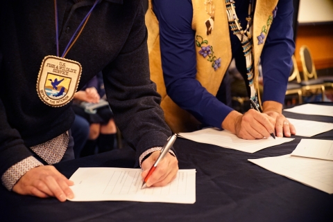 two people wearing regalia signing documents