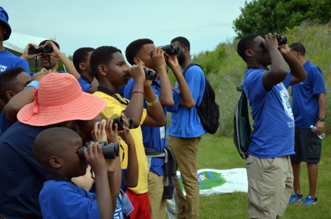 kids with binoculars looking toward trees