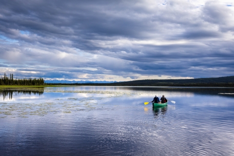 two people paddle a canoe on a large lake