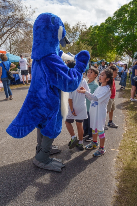 An image of a little girl and a little boy looking up at the Puddles the Blue Goose mascot