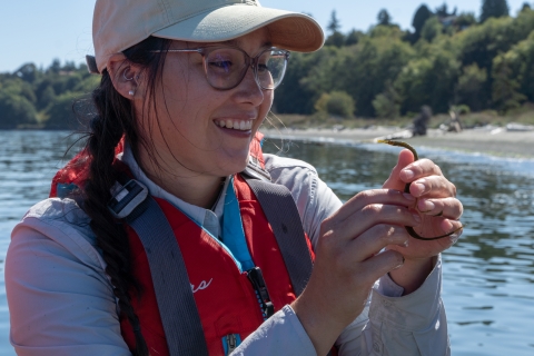 Service intern smiles while holding up a Bay Pipefish.