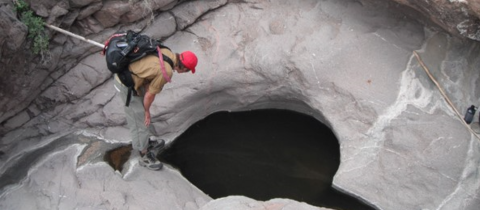 A researcher looks into a pool of water that is encased in rock