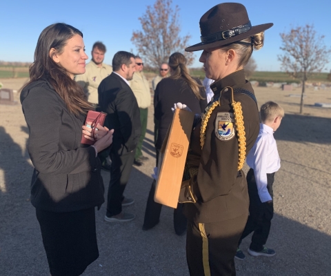 The wife of a fallen firefighter receives a flag from an Honor Guard member. 