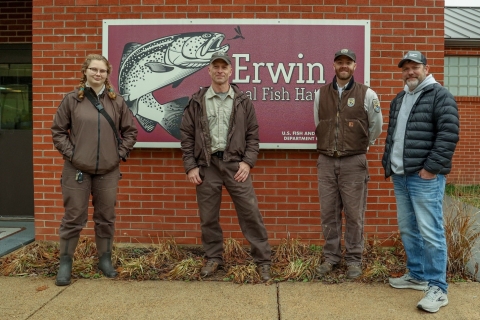 Erwin NFH and TVA staff stand in front of the Erwin National Fish Hatchery sign.