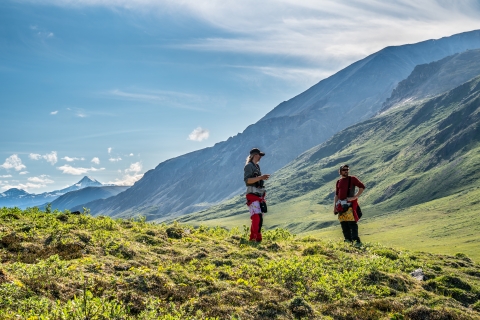 Two people stand at the top of a grassy hill near the Hulahula River in Alaska