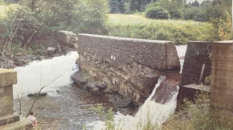 Stone dam in a river that has water flowing on either side.