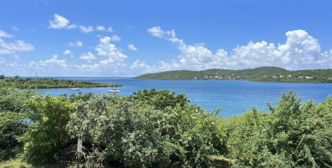 A stunning view showcasing the vibrant vegetation, majestic mountains, and the sparkling ocean at Culebra National Wildlife Refuge.