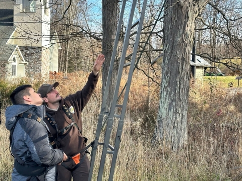 Mentee Adrian (L) learns about tree stand safety from Mentor Matt (R) as part of the Field to Fork mentored rifle deer hunt at Cherry Valley National Wildlife Refuge in December 2024.