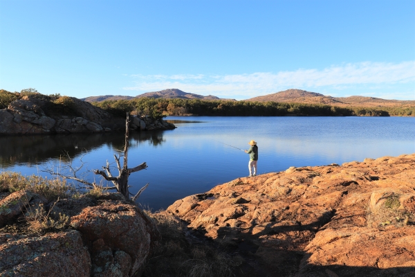 Fisherman standing on the rocky lake edge at Quanah Parker Lake.