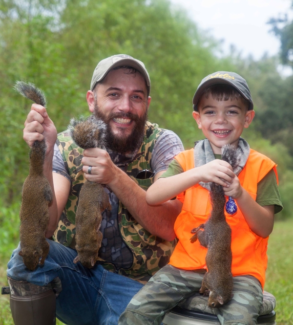 Man and young boy holding squirrels