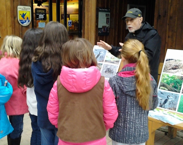 Volunteer educator talking to school group outside Visitor Center