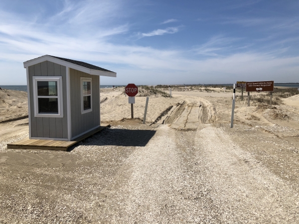 A booth sits to the left of a sandy entrance to the beach