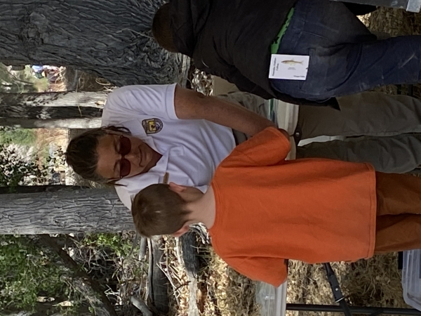 A ranger helping a young man learn about pupfish