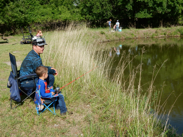 Adult and kid, fishing at Bonham Pond at Salt Plains National Wildlife Refuge during the Youth Fishing Derby.