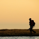 Silhouette of a person walking with a shotgun on the tundra