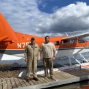 2 people stand in front of an airplane