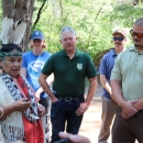 Several people stand in a circle around a woman wearing traditional Tribal garments