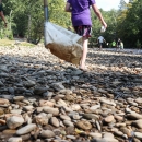 Students walking across a broad, rocky beach to a shallow river