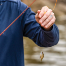 Adam Comer holds up small fish hooked while microfishing. 