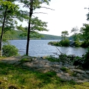 A view of the forested hills leads to a large open body of water below 