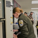 Woman in usfws uniform looks through microscope