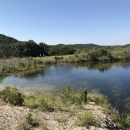 A large pool of water in a green, hilly landscape