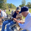 Two elderly men removing a hook from a fish