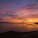 Sunset over the shore of a large river.