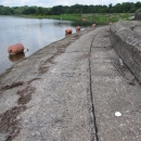 Curved cement infrastructure with green trees and a lake in distance