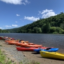 colorful kayas line the bank of a river with trees on the opposite bank