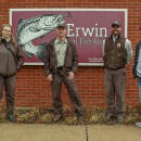 Erwin NFH and TVA staff stand in front of the Erwin National Fish Hatchery sign.