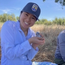 a woman smiles outside while holding a chick in her hands