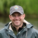 Smiling man wearing a USFWS baseball hat