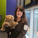 woman in USFWS sweater poses holding a brown bear puppet