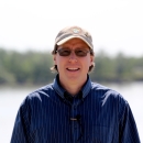 a man with a FWS hat in a blue shirt standing by a river