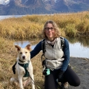 woman next to dog with mountains in the background