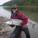 woman holding a big fish by a river