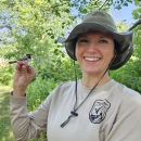 A female wildlife biologist holds a golden winged warbler.