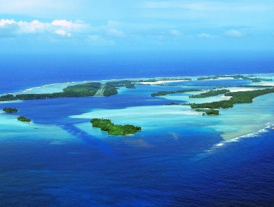 Aerial view of an island atoll surrounded by sandy reef in the deep blue ocean