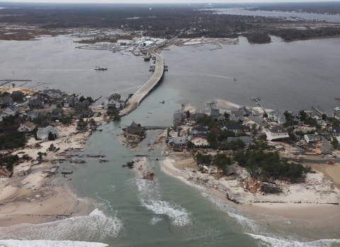 Aerial view of ocean breach surrounded by damaged beach front homes.