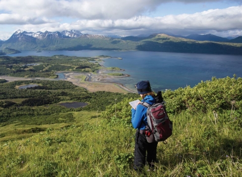 woman standing on hill overlooking view of lake on refuge